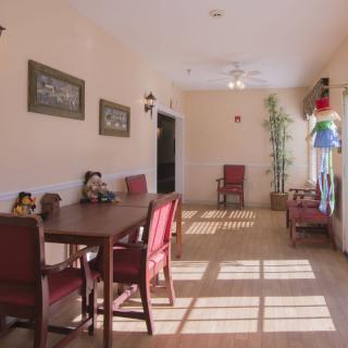 A well-lit dining area with red chairs and a table, adorned with decorative items and wall art.
