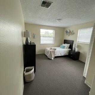 A minimalist bedroom with a single bed, dresser, and two windows.