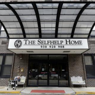 The entrance of The Selfhelp Home, featuring a clear awning and seating.