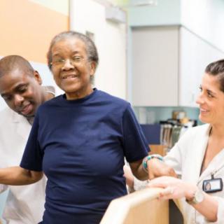 Healthcare professionals assisting an elderly woman with mobility exercises.