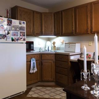 A cozy kitchen with wooden cabinets, a fridge adorned with magnets, and decorative candles on the table.