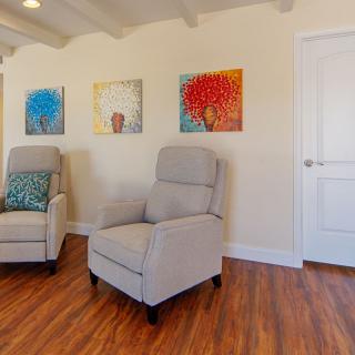 A cozy living room with comfortable armchairs and colorful artwork on the walls.