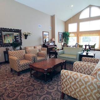 A cozy living room with patterned chairs, a sofa, and large windows.