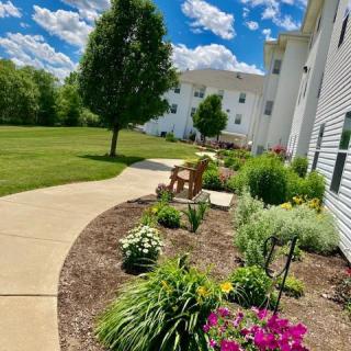A beautifully landscaped garden path with flowers and trees alongside a building under a blue sky.