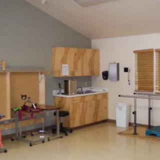 A clean and organized clinic room with examination tables and medical equipment.