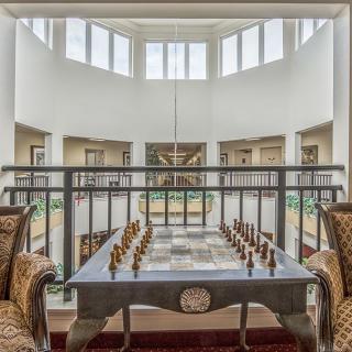 A beautifully designed interior featuring a chess game setup with elegant seating, surrounded by large windows.
