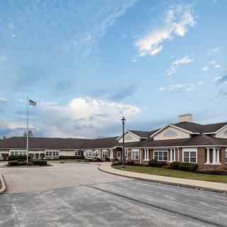 A wide shot of a large building with a driveway under a partly cloudy sky.