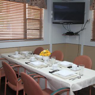 A beautifully set dining table in a restaurant, featuring a television and natural light from wooden blinds.