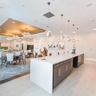 A modern, luxurious kitchen and dining area featuring an island counter, elegant chandeliers, and open space design.
