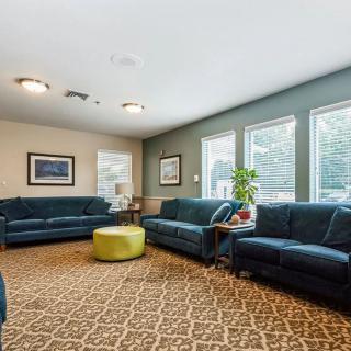 A cozy living room with multiple couches, large windows, and a patterned carpet.