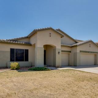 A single-story suburban house with a beige exterior and a well-maintained yard under a clear blue sky.