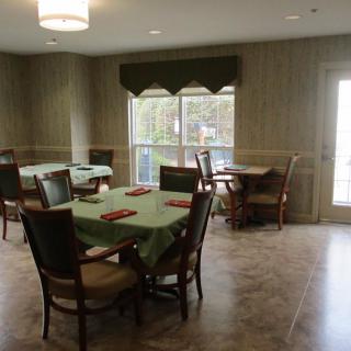 A cozy dining room with neatly arranged tables and chairs near a large window.