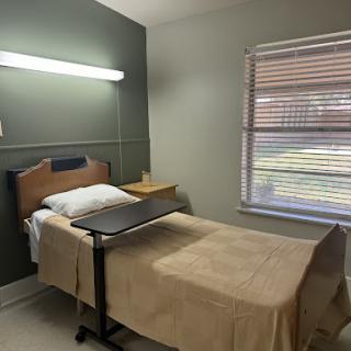 A clean and simple patient room in a healthcare setting, featuring a hospital bed and natural light from the window.