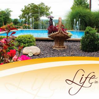 A serene garden featuring a swimming pool, vibrant flowers, and a peaceful fountain.