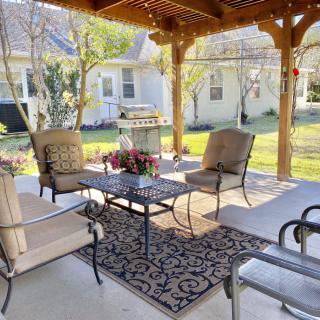 A cozy patio setup with comfortable seating under a pergola, perfect for outdoor relaxation.
