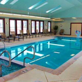 A serene indoor swimming pool with comfortable seating and ample natural light.