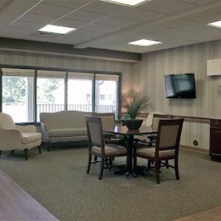 A cozy and welcoming lobby area with comfortable seating and a round table, illuminated by natural light.