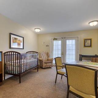A cozy nursery room featuring a crib, armchair, and dining table.