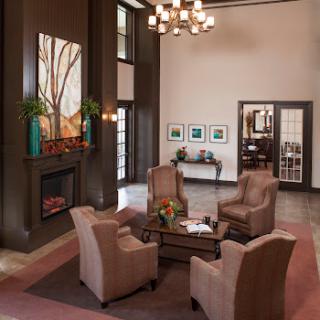 A modern hotel lobby featuring comfortable seating, elegant artwork, and a warm fireplace.