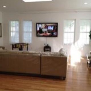 A cozy living room featuring a comfortable sofa and a television, illuminated by natural light.