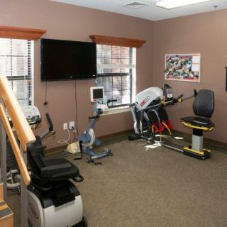 A small fitness room equipped with various exercise machines and a TV.