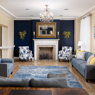A stylishly decorated living room featuring a fireplace, sofas, armchairs, and a chandelier.