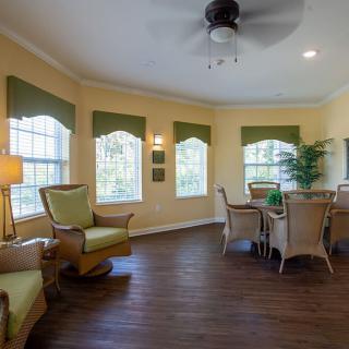 A cozy living room with wicker furniture and large windows allowing natural light.