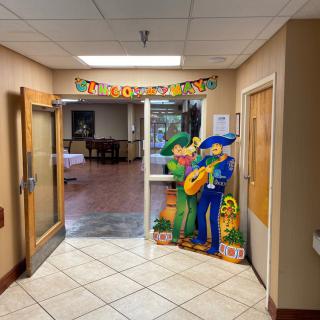 A decorated hallway entrance with colorful cardboard cutouts and a festive banner.