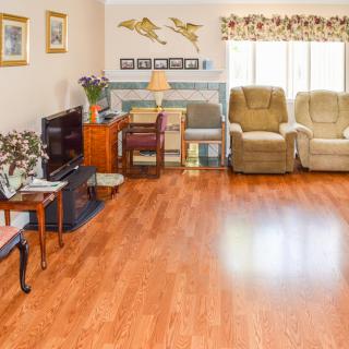 A cozy living room with hardwood floors, featuring recliner chairs, a television, and decorative elements.