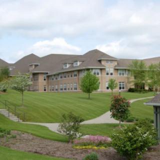 A scenic view of a campus building surrounded by lush greenery and walkways.