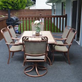 A cozy outdoor patio setup with a table, chairs, and a grill on the deck.