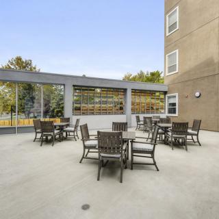 An outdoor patio with multiple tables and chairs near a building.