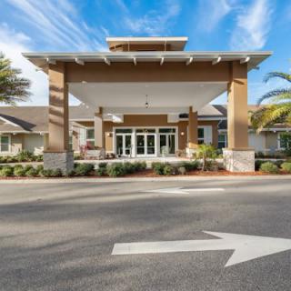 A modern building entrance with a covered driveway and landscaped surroundings.