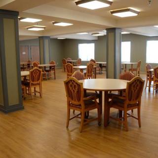 A spacious dining area with wooden tables and chairs, well-lit by overhead lights.