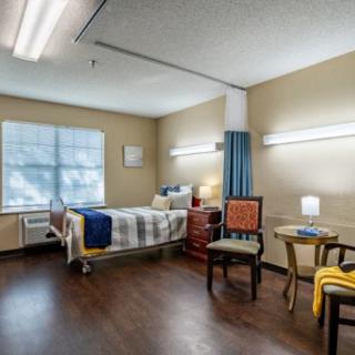 A well-lit hospital room with a patient bed and comfortable seating.