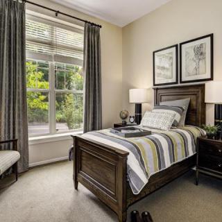 A cozy bedroom with a single bed, large window, and tasteful decor.
