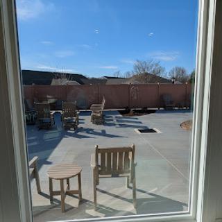 A sunny patio view with wooden chairs and a clear blue sky.