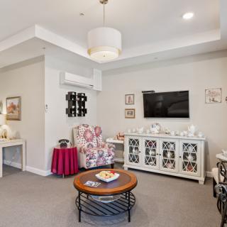 A cozy living room with modern decor, featuring a TV, armchair, coffee table, and stylish wall art.
