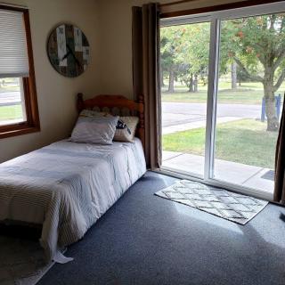 A cozy bedroom with a single bed and ample natural light from a sliding glass door.
