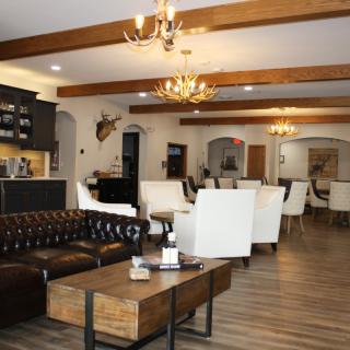 A cozy lounge area with a mix of leather and fabric seating, wooden beams, and elegant chandeliers.