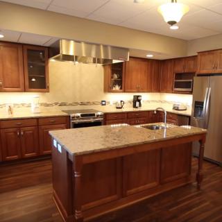 A modern kitchen with wooden cabinets, a central island, and stainless steel appliances.