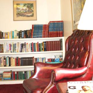 A cozy library corner with a leather chair and a bookshelf filled with books.