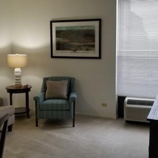 A cozy living room with a lamp, armchair, and artwork on the wall.