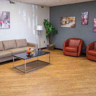 A modern waiting area featuring a beige sofa, red armchairs, and a glass coffee table.