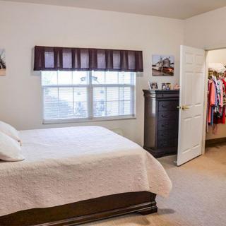 A cozy bedroom with a bed, dresser, and open closet.