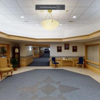 A spacious lobby area with chairs, a chandelier, and a corridor leading further inside.