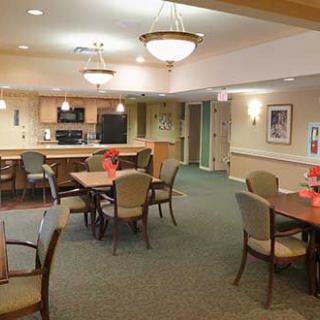 A community dining area with several tables and chairs, adjacent to a kitchen.
