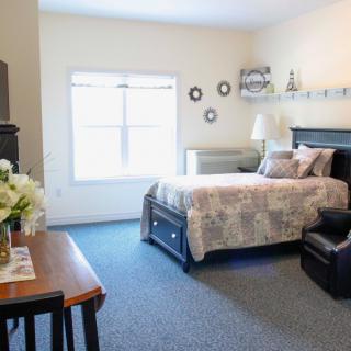 A cozy bedroom with a neatly made bed, a window letting in natural light, and simple decor.