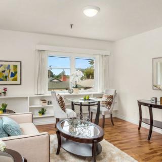 A modern living room with elegant furniture and a wooden floor, featuring a comfortable sofa and a small dining table by the window.