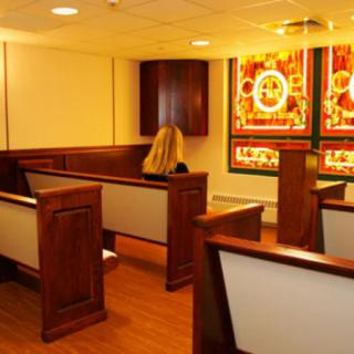 A quiet chapel interior with wooden pews and colorful stained glass windows.